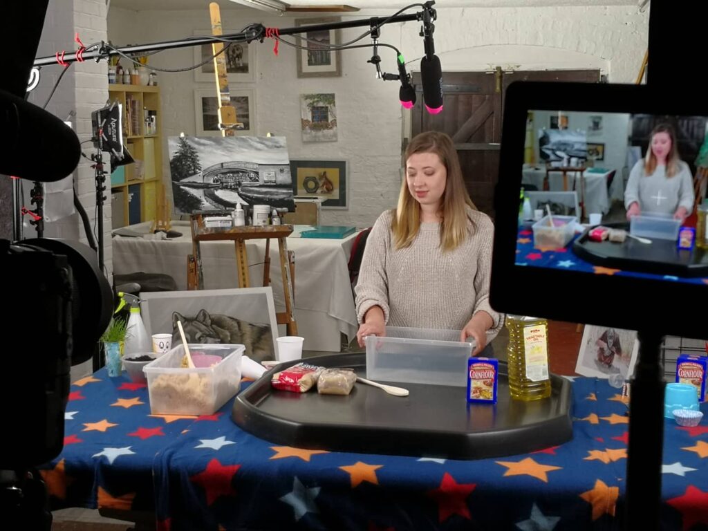 Behind the scenes shot of an actor being filmed doing sensory activities for kids