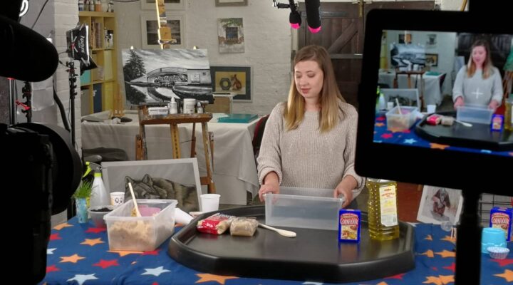 Behind the scenes shot of an actor being filmed doing sensory activities for kids